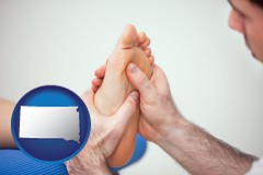 south-dakota map icon and a podiatrist practicing reflexology on a human foot